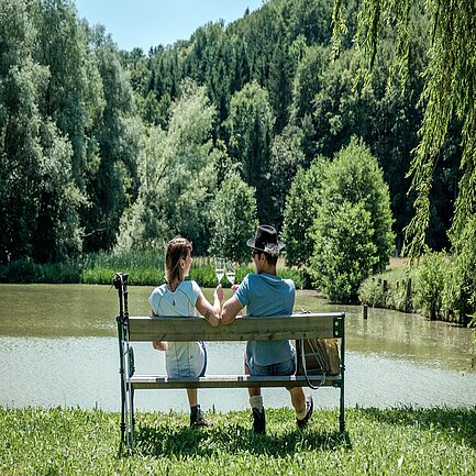 Pärchen sitzt auf einer Bank am See in der Region Loipersdorf