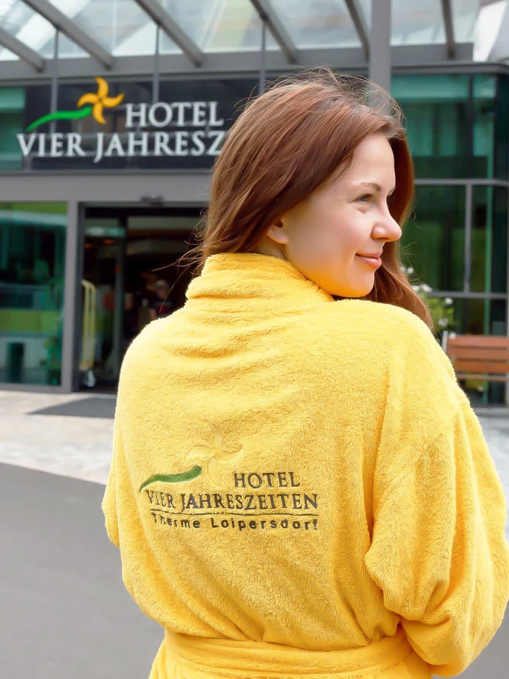 Frau im Bademantel vorm Thermenhotel Vier Jahreszeiten